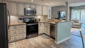 A modern kitchen with stainless steel appliances, light wood cabinetry, and a large island. - Sunset Rentals | Continental Club 16 (Hilton Head Island)