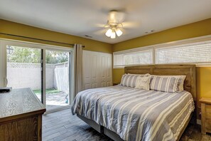 A bedroom with a bed, a nightstand, a desk, and a ceiling fan.