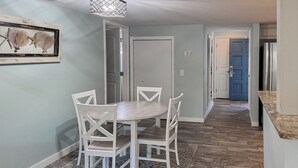 A dining area with a round table and four chairs, a light-colored rug, and a framed artwork on the wall. - Sunset Rentals | Continental Club 16 (Hilton Head Island)