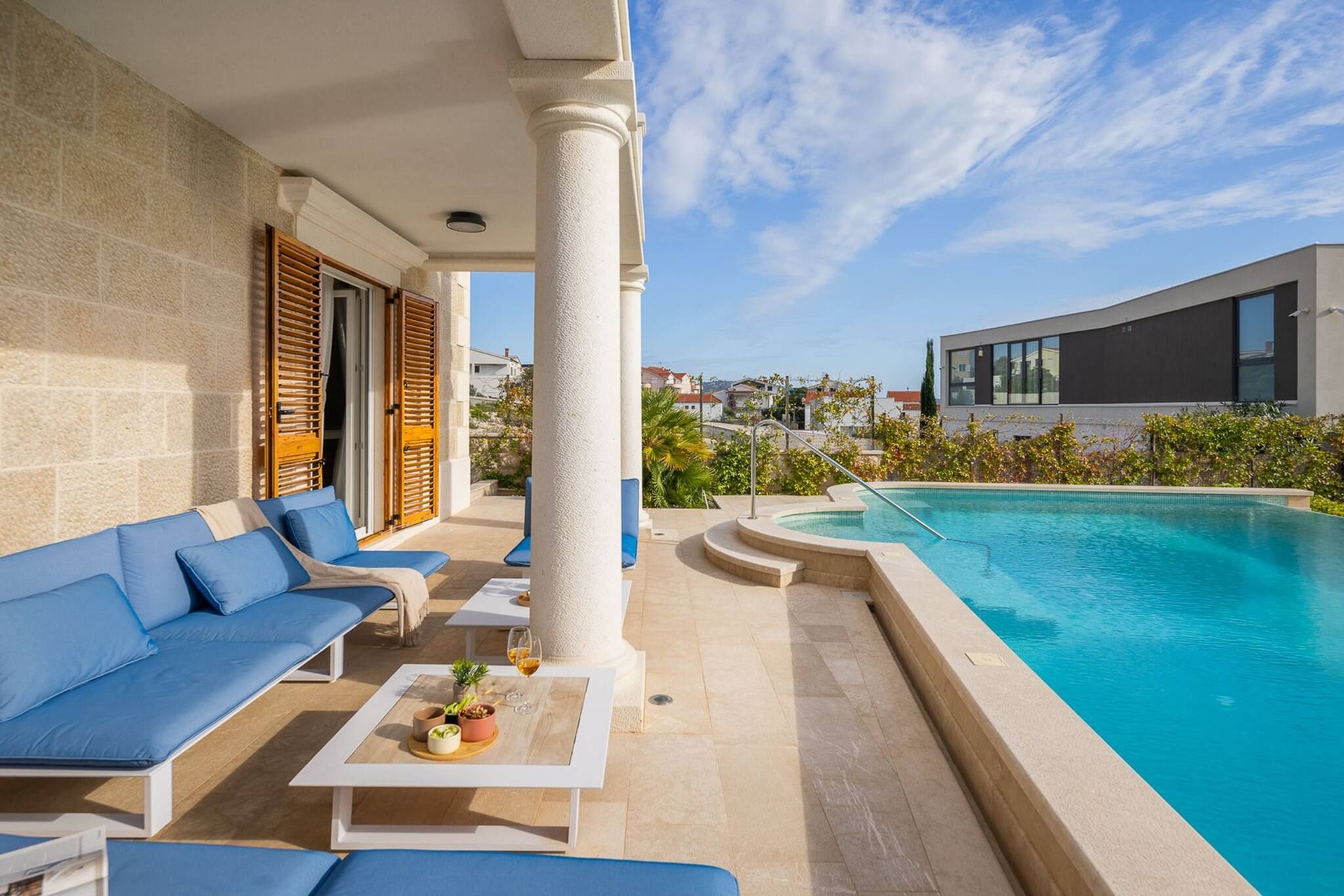 A poolside area with a modern pool, a sofa, and a table with a drink.