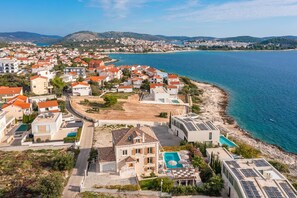 A coastal residential area with houses, a swimming pool, and a view of the sea.