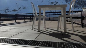 A table and chairs on a concrete platform with a metal railing, overlooking a snow-covered mountain. - 10m from resort center, 2nd floor, balcony, tv, ski locker, 28m², Tignes (Tignes)
