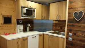 A compact kitchen with wooden cabinets, a microwave, a coffee maker, and a sink. - 10m from resort center, 2nd floor, balcony, tv, ski locker, 28m², Tignes (Tignes)