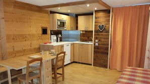 A compact room with a wooden interior, a kitchenette, a dining area, and a bed. - 10m from resort center, 2nd floor, balcony, tv, ski locker, 28m², Tignes (Tignes)