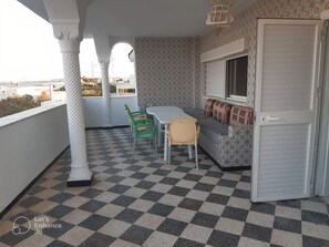 A balcony with a checkered floor, a table, chairs, and a patterned wall. - Superbe Maison Avec vue Panoramique (Al Haouaria)
