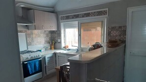 A kitchen with a gas stove, oven, and a sink. There is a window with a view of the outside.