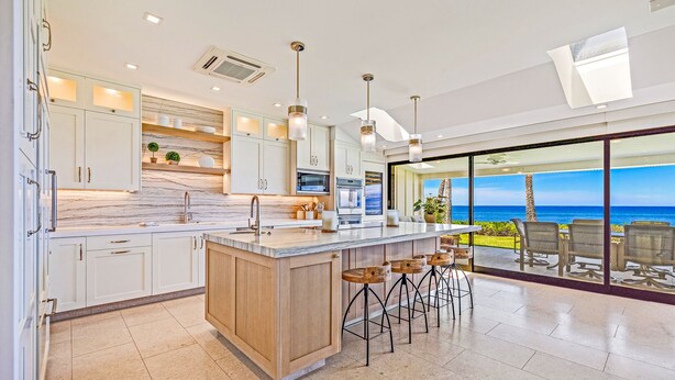 Una cocina moderna con una isla grande, taburetes de bar y vistas al océano.