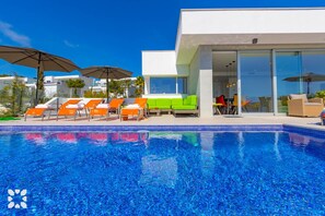 Een modern hotel met een zwembad, terras en een serre-achtige eetruimte.