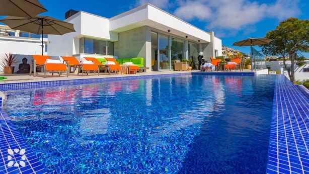 Ein moderner Poolbereich mit klarem, blauem Wasser, Liegestühlen und Sonnenschirmen.