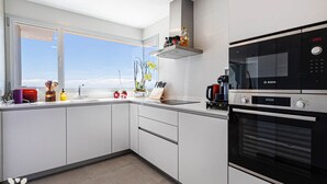 Eine moderne Küche mit weißen Schränken, einer Bosch-Mikrowelle und einem großen Fenster mit Blick.