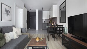 A modern living room with a grey sofa, a wooden coffee table, and a flat-screen TV. - Elite Apartments Stępkarska Premium (Gdansk)