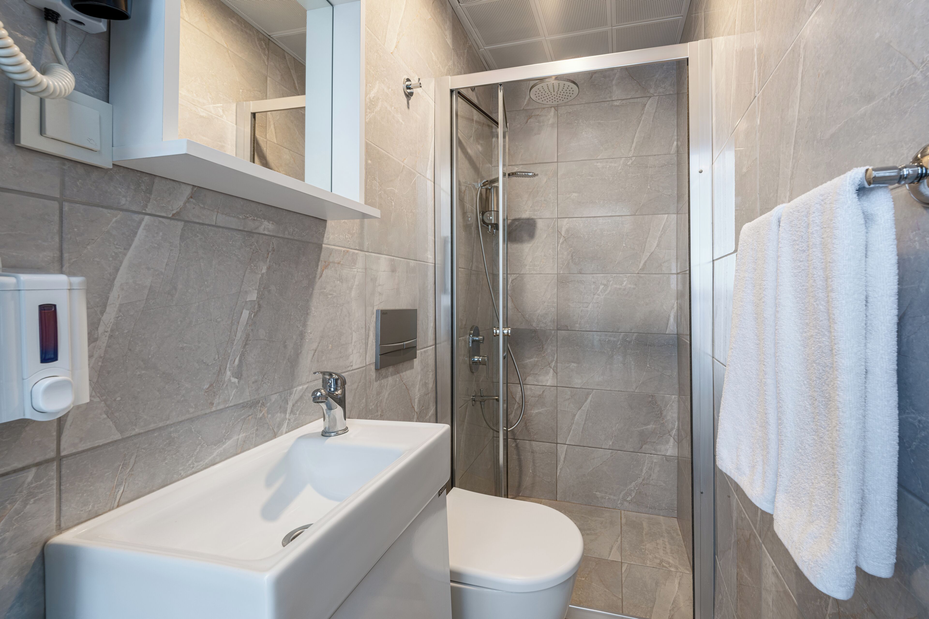 A modern bathroom with a glass-enclosed shower, a white sink, and a toilet.