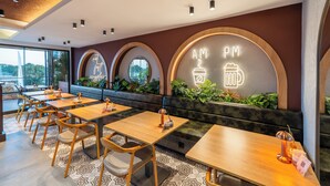 A modern restaurant with wooden tables and chairs, a neon sign, and a view of greenery outside. - Echinus Lara Hotel (Antalya)