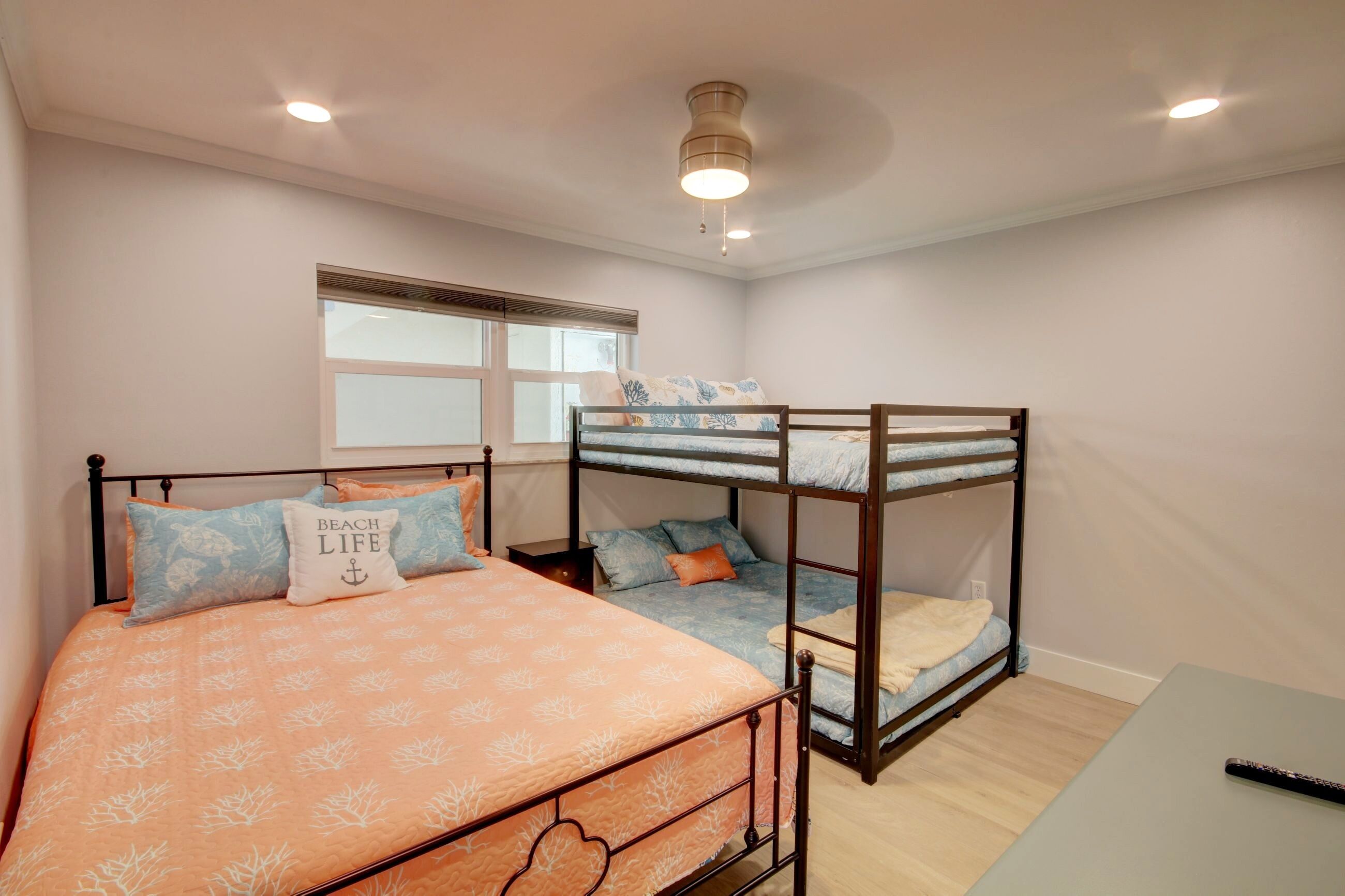 Une chambre avec un lit superposé, un lit simple et une petite table.