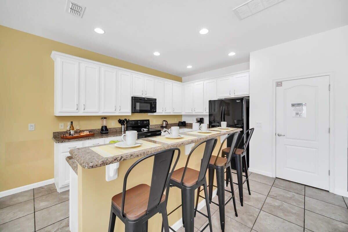 A modern kitchen with white cabinets, a granite countertop, and a built-in microwave.