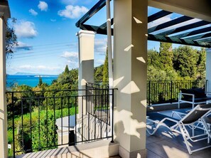 A balcony with a view of the sea and greenery, a pergola, and outdoor seating. - Villa Afionas (Corfu)