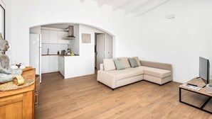 A modern living room with a beige sectional sofa, a wooden coffee table, and a flat-screen TV.