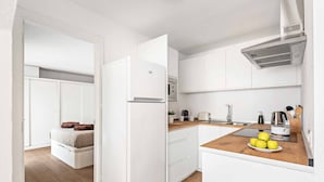 A compact kitchen with white cabinets, a built-in oven, and a wooden countertop.