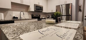 A modern kitchen with granite countertops, stainless steel appliances, and decorative family-themed placemats. - Breath taking views!!! (Kissimmee)