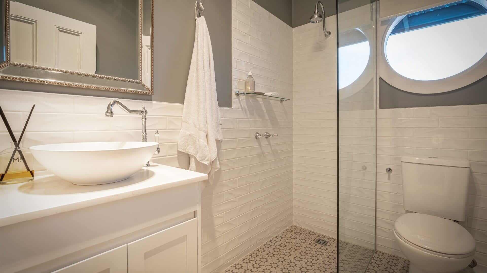 A bathroom with a white sink, a mirror, a towel, a shower, and a toilet.