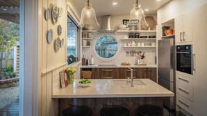 Una cocina moderna con una isla central, iluminación colgante y vistas al exterior.