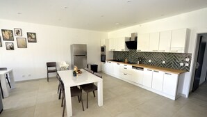 A modern kitchen with white cabinets, a herringbone backsplash, and a central island with seating. - Gîte Trieves/ Gîte La Passerelle / Gîte Lavars (Lavars)