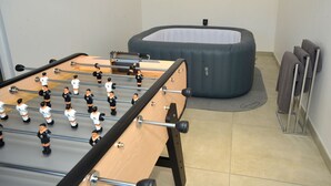 A foosball table and a large inflatable pool in a room with tiled flooring and a towel rack. - Gîte Trieves/ Gîte La Passerelle / Gîte Lavars (Lavars)