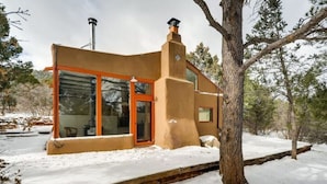 Ein modernes Haus mit Glastür und -fenstern, umgeben von Schnee und Bäumen.