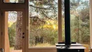 A rustic cabin interior with a large window, a chimney, and a brick floor.