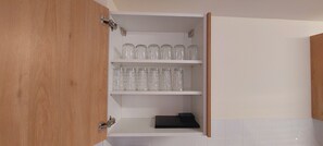 The kitchen cabinet features two shelves, one holding glass jars and the other a tray.