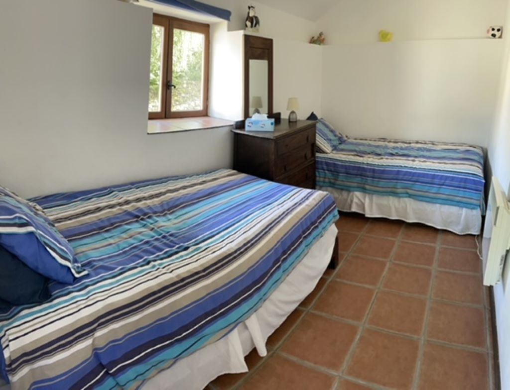 Une chambre avec deux lits, une commode, une fenêtre et un miroir.
