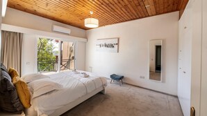 A bedroom with a wooden ceiling, a bed with white bedding, a small stool, and a framed picture on the wall. - Platres Forest Panorama (Platres)