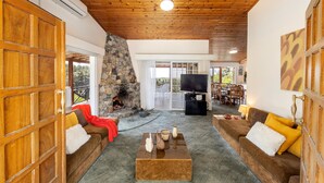 A spacious living room with a stone fireplace, wooden ceiling, and a cozy seating area. - Platres Forest Panorama (Platres)
