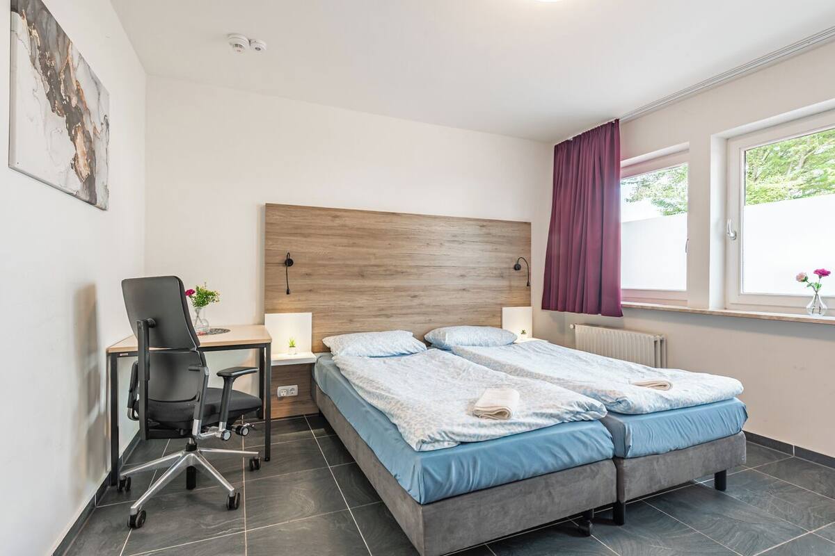 A modern hotel room with a large bed, a desk, and a chair.