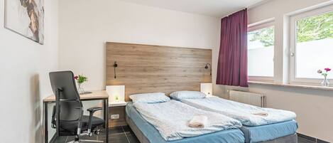 A modern hotel room with a large bed, a desk, and a chair.