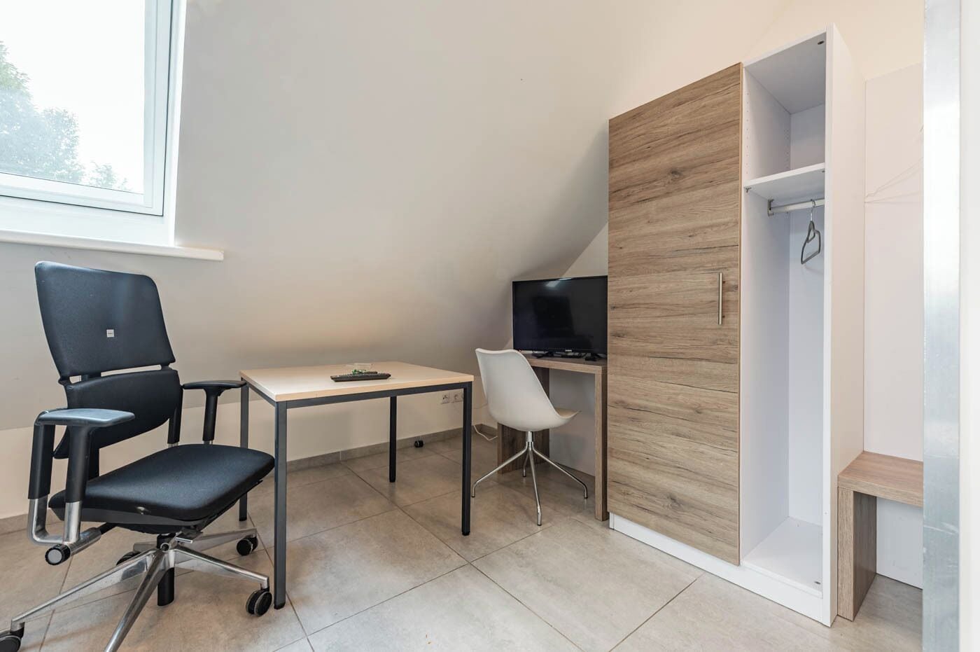 A modern office space with a desk, two chairs, a television, and a wardrobe.