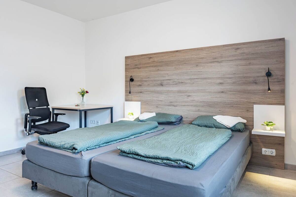 A modern bedroom with a large bed, a desk, and a chair.