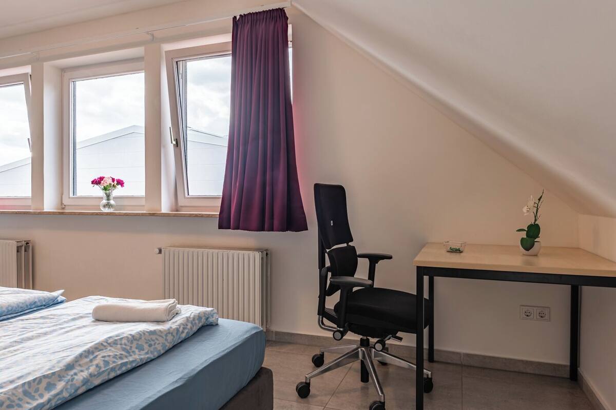 A bedroom with a bed, a desk, and a chair.