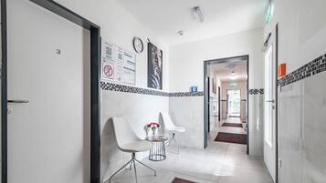 A hotel corridor with a reception desk, a clock, and a sign with QR codes.