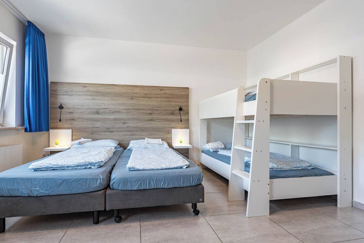 A room with two beds, a bunk bed, and a wooden headboard.