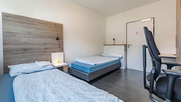 Habitación de hotel con dos camas, un escritorio y una silla.