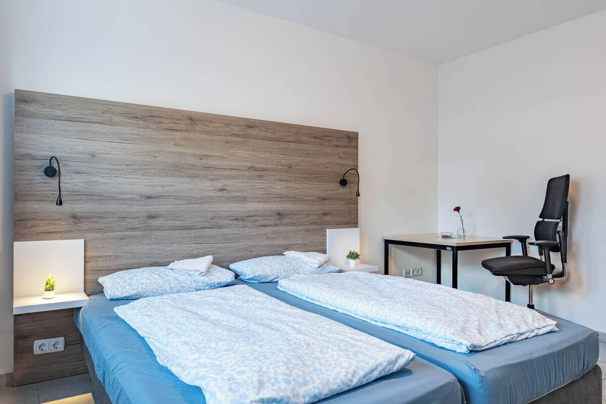 A hotel room with a large bed, a desk, a chair, and a small table with a vase of flowers.