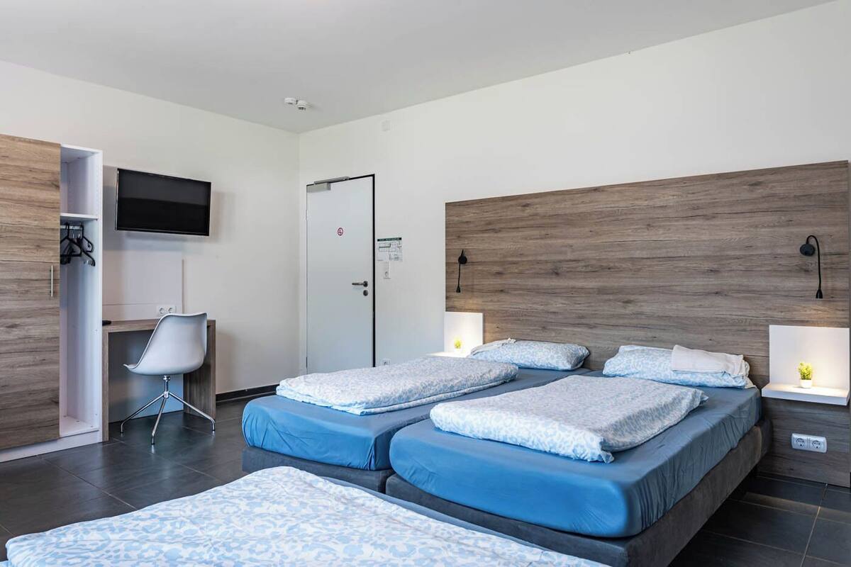 A hotel room with two beds, a desk, a TV, and a wardrobe.