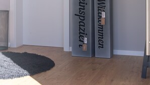 Een gang met een witte deur, een zwart-wit vloerkleed en twee grijze pilaren met de tekst 'Hareispaier' en 'Wienerinnen'.