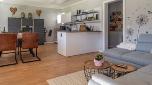Een moderne keuken met een centraal eiland, een zithoek met bruine leren stoelen, een grijze bank en een klein bijzettafeltje.