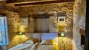Een landelijke kamer met een stenen muur, een bed met twee kussens en twee bedlampen.