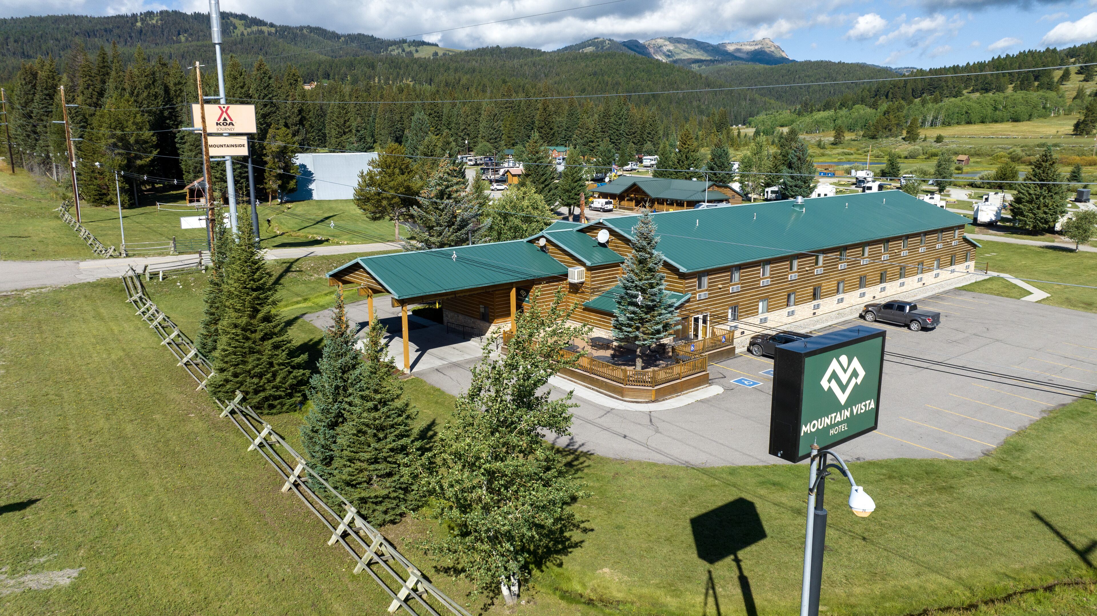 A Mountain Vista Hotel with a large building, covered parking, and a view of surrounding mountains.