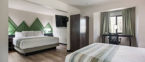 A hotel room with a large bed, a desk, a wardrobe, and a television on the wall.