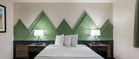 A hotel room with a large bed, two bedside tables with lamps, and a green accent wall.