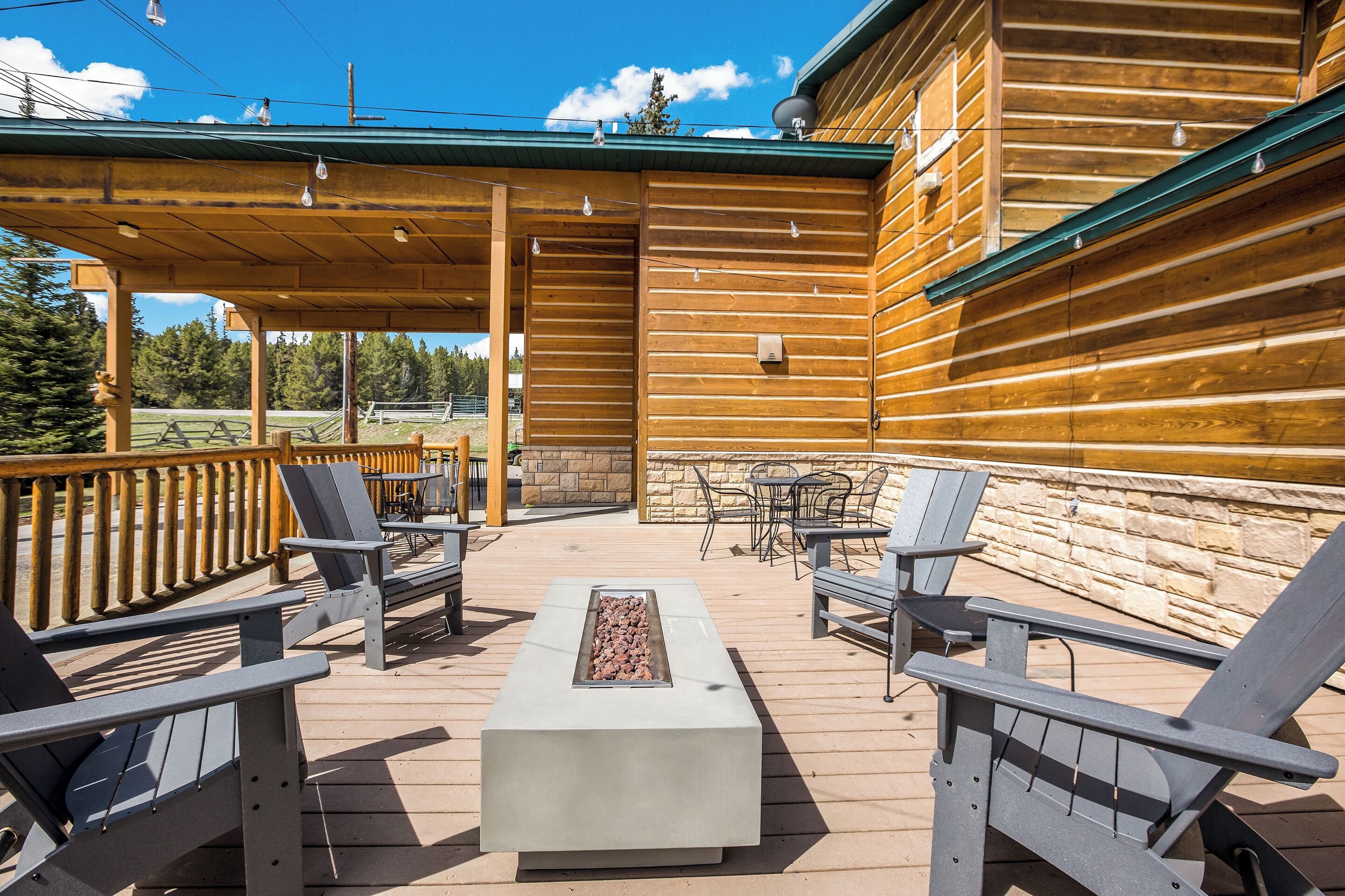 A wooden deck with Adirondack chairs, a fire feature, and a stone wall.